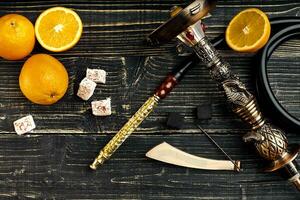 Dismantled parts of hookah on a wooden background with orange fr photo