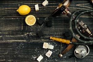 Arabic hookah with a tobacco flavor of a mixture of lemon. Top view of a dark wooden background photo