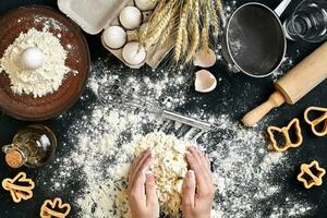 Woman's hands knead dough on table with flour, eggs and ingredients. Top view. photo