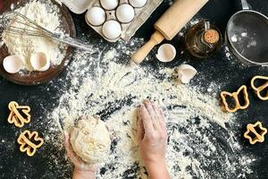 mujer manos amasar masa en mesa con harina, huevos y ingredientes. parte superior vista. foto