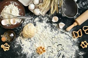 Cooking dough for cookies, butter, eggs, cooking equipment, flour on a black table. Top view with copy space, mockup for menu, recipe or culinary classes. Baking background. photo