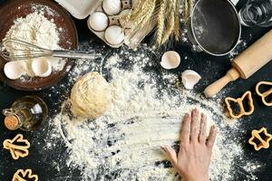 Woman's hands knead dough on table with flour, eggs and ingredients. Top view. photo