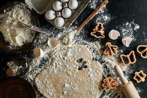 Dough for ginger biscuits rolled up on a table and cut using molds photo