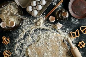 Cooking dough for cookies, butter, eggs, cooking equipment, flour on a black table. Top view with copy space, mockup for menu, recipe or culinary classes. Baking background. photo