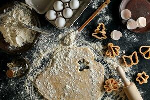 Dough for ginger biscuits rolled up on a table and cut using molds photo