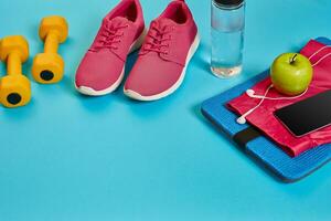 Healthy concept, diet plan with sport shoes and bottle of water and dumbbells on blue background, healthy food and exercise concept photo