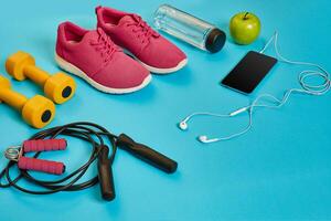 Flat lay of dumbbell, bottle of water, jump rope and sneaker, sport equipments, fitness items, top view photo