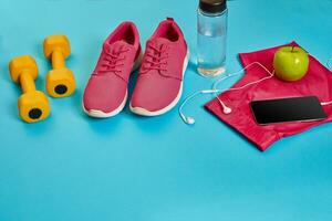 Healthy concept, diet plan with sport shoes and bottle of water and dumbbells on blue background, healthy food and exercise concept photo