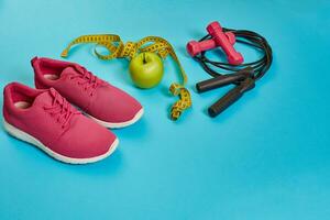 Flat lay of dumbbell, bottle of water, jump rope and sneaker, sport equipments, fitness items, top view photo