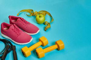 Flat lay of dumbbell, bottle of water, jump rope and sneaker, sport equipments, fitness items, top view photo