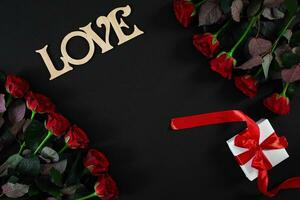 Red roses flowers with wooden word LOVE on black background with photo