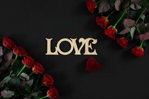 Red roses flowers with wooden word LOVE on black background with photo