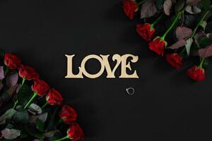 Red roses flowers with wooden word LOVE on black background with photo