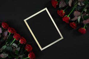 Red roses and empty chalk board on black background. Valentines photo