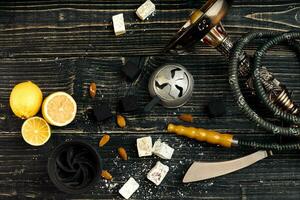 Arabic hookah with a tobacco flavor of a mixture of lemon. Top view of a dark wooden background photo