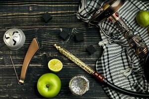 Arabic hookah with a tobacco flavor of a mixture of lime and apple. Top view of a dark wooden background photo