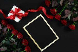 Red roses and empty chalk board on black background. Valentines photo