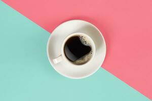 A cup of black coffee on blue and pink background. View from above. photo