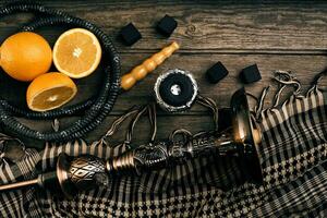 Dismantled parts of hookah on a wooden background with orange fr photo