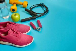 Flat lay of dumbbell, bottle of water, jump rope and sneaker, sport equipments, fitness items, top view photo