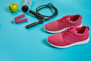 Flat lay of dumbbell, bottle of water, jump rope and sneaker, sport equipments, fitness items, top view photo