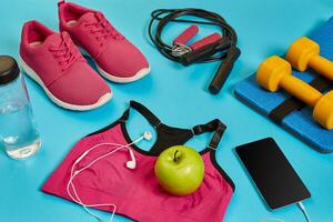 Flat lay of dumbbell, bottle of water, jump rope and sneaker, sport equipments, fitness items, top view photo