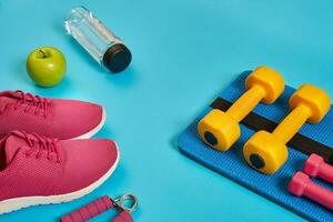 Healthy concept, diet plan with sport shoes and bottle of water and dumbbells on blue background, healthy food and exercise concept photo