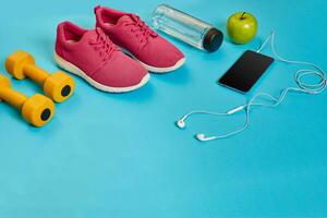 Healthy concept, diet plan with sport shoes and bottle of water and dumbbells on blue background, healthy food and exercise concept photo