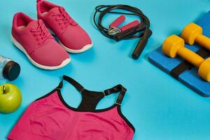 Flat lay of dumbbell, bottle of water, jump rope and sneaker, sport equipments, fitness items, top view photo