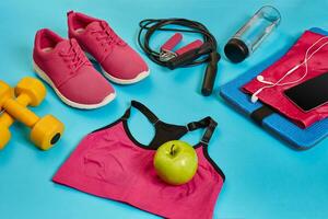 Flat lay of dumbbell, bottle of water, jump rope and sneaker, sport equipments, fitness items, top view photo