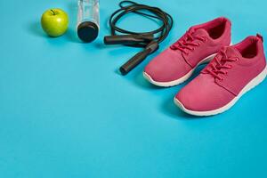 Flat lay of dumbbell, bottle of water, jump rope and sneaker, sport equipments, fitness items, top view photo