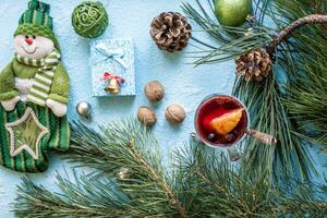 Hot mulled wine with orange, anise, cardamon and cinnamon on blue background. Christmas tree branches, gifts and cones. photo