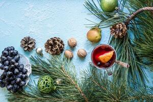 Hot mulled wine with orange, anise, cardamon and cinnamon on blue background. Christmas tree branches, gifts and cones. photo