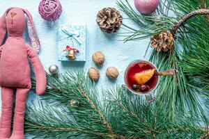 Hot mulled wine with orange, anise, cardamon and cinnamon on blue background. Christmas tree branches, gifts and cones. photo