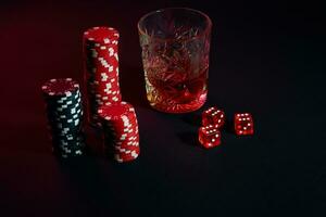 Poker chips and wine glass of cognac on dark table. Gambling photo