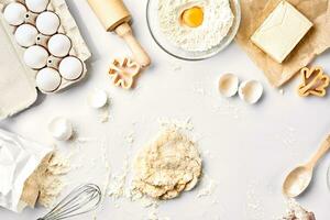 Raw dough ready for kneading on white table. Bakery ingredients, eggs, flour, butter. Shapes for making cookies. photo