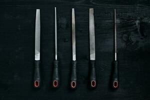 Series of many sharp steel blades on black wooden background photo