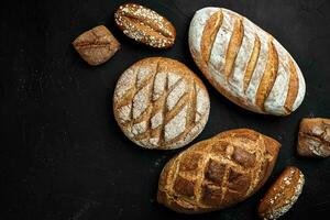 Bakery - gold rustic crusty loaves of bread and buns on black chalkboard background. photo