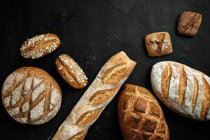 Bakery - gold rustic crusty loaves of bread and buns on black chalkboard background. photo