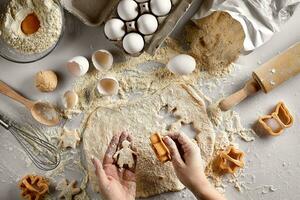 Baking preparation. Raw dough and cutters for the holiday cookies on a white table. Top view. photo