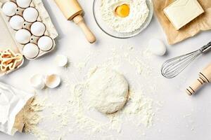 Raw dough ready for kneading on white table. Bakery ingredients, eggs, flour, butter. Shapes for making cookies. photo