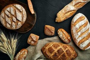 Bakery - gold rustic crusty loaves of bread and buns on black chalkboard background. photo