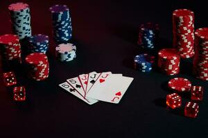 Casino chips and cards on black table surface. Gambling, fortune, game and entertainment concept - close up photo