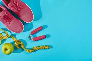 Sneakers with measuring tape on cyan blue background. Sport shoes and sportive equipment for healthy shape. photo