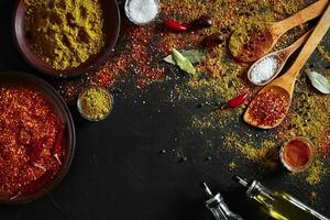 Set of indian spices on black background - green cardamom, turmeric powder, coriander seeds, cumin, and chili, top view photo