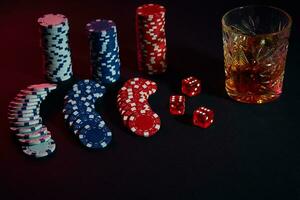 Poker chips and wine glass of cognac on dark table. Gambling photo