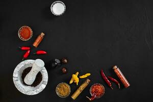 Various spices and mortar on black background with copy space photo