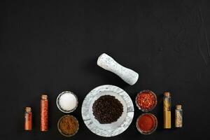 Various spices and mortar on black background with copy space photo