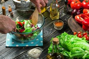 Man preparing salad with fresh vegetables on a wooden table. Cooking tasty and healthy food. Close-up photo