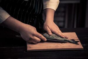 cocinero corte el pescado en un tablero foto